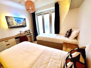 een slaapkamer met 2 bedden, een bureau en een wastafel bij Parisien Hôtel style in Pré Saint Gervais
