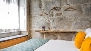 1 dormitorio con pared de piedra, cama y ventana en My Ribeira Guest House, en Oporto