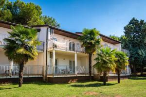 un edificio con palme di fronte ad esso di Ai Pini Medulin Resort a Medulin