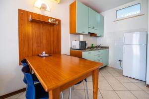 a kitchen with a wooden table and a refrigerator at Ai Pini Medulin Resort in Medulin