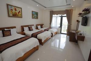 a hotel room with three beds and a television at Phong Nha Jasmine Hostel & Roof Top Bar in Quang Binh