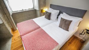 a bed with a white comforter and pillows at My Ribeira Guest House in Porto