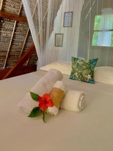 a bed with two towels and a flower on it at Aurora Lodge in Ile aux Nattes