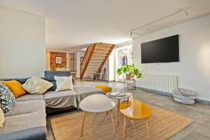 a living room with a couch and a tv at Maison Rioma - Grande maison à 200m de la plage in Plounéour-Trez