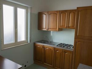eine Küche mit Holzschränken, einem Waschbecken und einem Fenster in der Unterkunft Residenza Arena Bianca in Santa Maria