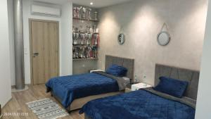 - une chambre avec 2 lits avec des draps bleus et une étagère dans l'établissement L'Écrin de Paradis, à Sousse
