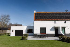 una casa blanca con una mesa en el patio en Maison Victor, en Koksijde