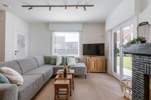 a living room with a couch and a tv at Maison Victor in Koksijde