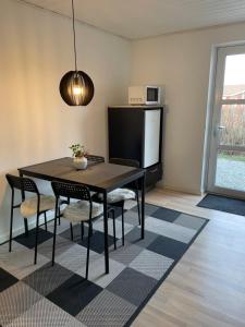 a dining room table with chairs and a refrigerator at Værelser i Fynshav in Augustenborg