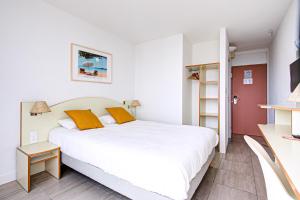 een slaapkamer met een groot wit bed met oranje kussens bij Hotel Centre Plage in Argelès-sur-Mer