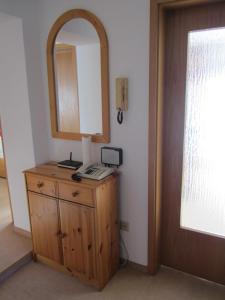a wooden dresser with a mirror and a telephone on it at Ferienwohnung Berger in Oberstaufen +39 photos