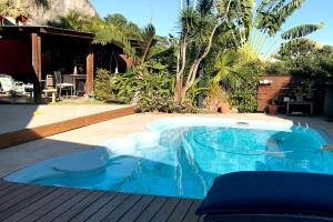 a blue swimming pool in a yard next to a house at Villa L'arbre du voyageur -Grande piscine privée vue imprenable sur l'Ocean indien in Saint-Leu