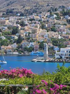 a view of a town on the water with pink flowers at The Anchor House in Symi