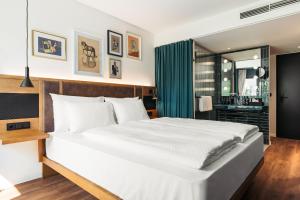 a bedroom with a large white bed and a bathroom at Hotel Schani Uno City in Vienna