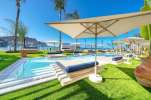 ein Resortpool mit Liegestühlen und einem Sonnenschirm in der Unterkunft Labranda Costa Mogan in Playa del Cura