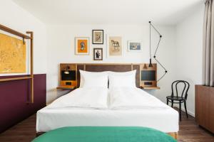 a bedroom with a large white bed and a chair at Hotel Schani Uno City in Vienna