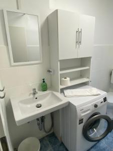 ein weißes Badezimmer mit einem Waschbecken und einer Waschmaschine in der Unterkunft CaJu-Stays Monteurwohnung - Barntrup, Blumenstr. 1b in Barntrup