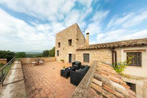 an outdoor patio with couches and tables on a building at Mas Coquells Habitación doble de 2 camas in Vilanant +8 photos