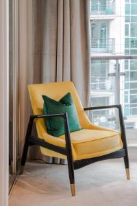 a yellow chair with a green pillow in a room at BEST THAMES VIEW in TOWN! LARGE LUXXE NOMAD DESIGN FAMILY HOME in London