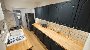 a kitchen with black cabinets and a wooden counter top at City Centre with Hot Tub - 3 Bed in Kent