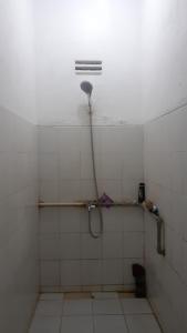 een badkamer met een douche in een wit betegelde kamer bij Penginapan Wanita Putri Salju Hostel Semarang in Semarang