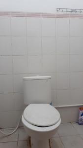 een wit toilet in een wit betegelde badkamer bij Penginapan Wanita Putri Salju Hostel Semarang in Semarang