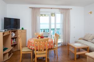 sala de estar con mesa, sillas y sofá en Apartments Waterfront Ivan, en Podgora