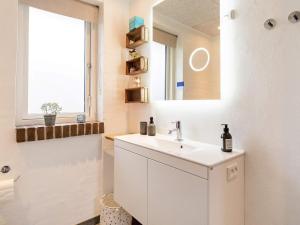 Holiday home Thyholm XXVIII في Thyholm: حمام أبيض مع حوض ومرآة