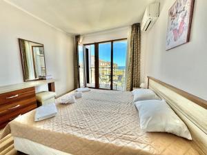 a bedroom with a large bed with a large window at Sunshine apartment in Shkorpilovtsi