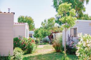 un giardino con due case bianche e alberi di Toscana Bella Camping Village a Vada