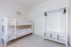 two white bunk beds in a white room at Flat Vigó in De Panne