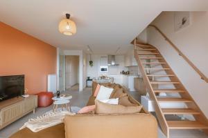 a living room with a couch and a staircase at Flat Vigó in De Panne