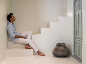 un homme assis sur les escaliers à côté d'un vase dans l'établissement Smiling Sparrows 1 and 2 Bedroom Villas, à Udaipur