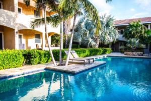 a swimming pool with a bench and palm trees at CocoCasa 22 Stylish Luxury Apartment with Pool near Jan Thiel Beach in Willemstad