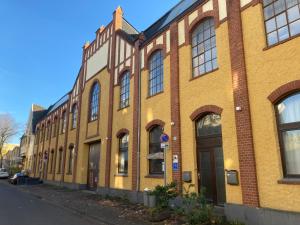 un edificio de ladrillo amarillo con ventanas en una calle en *-Sustainable Living/S-Home/SchälSick/Haus Frieda en Bonn