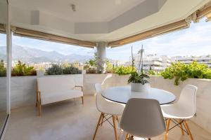 Biały stół i krzesła na balkonie z widokiem na góry w obiekcie Lujoso Apartamento con piscina en Paseo Maritimo Marbella w Marbelli