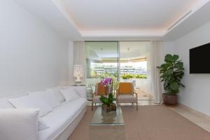 Biały salon z białą kanapą i telewizorem w obiekcie Lujoso Apartamento con piscina en Paseo Maritimo Marbella w Marbelli