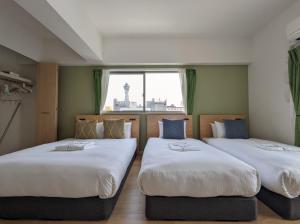 two beds in a room with a window at ESLEAD HOTEL Namba South Ⅰ in Osaka