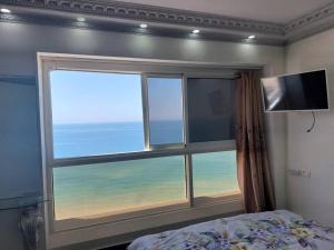 a bedroom with a window with a view of the ocean at Leonardo hotel , Very luxury suite, high floor, in fron of See in Bat Yam