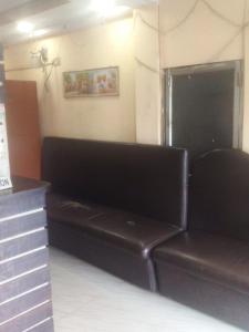 a brown leather couch in a room with a wall at Hotel Raj Airport in kolkata