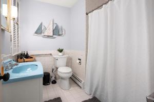 a bathroom with a shower curtain with a toilet and a sink at Federal on Exeter Circa 1805 Sleeps 8 in Exeter
