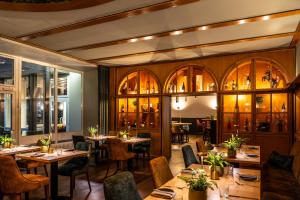 ein Restaurant mit Holztischen und -stühlen und Fenstern in der Unterkunft Uferdeck - Boutique Hotel in Traben-Trarbach