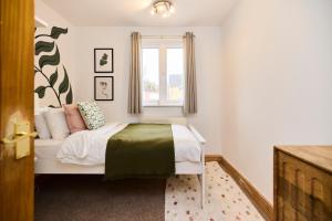 a small bedroom with a bed and a window at The Enfield Place - Elegant 4BDR House with Garden in Winchmore Hill