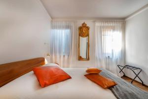 1 dormitorio con 1 cama con almohadas de color naranja y espejo en Italianflat - Duomo Deluxe en Verona