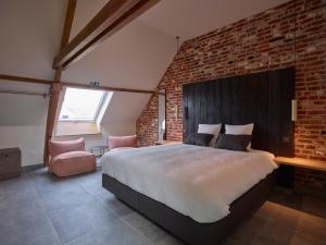 1 dormitorio con 1 cama grande y pared de ladrillo en De neering hoeve vakantiewoning, en Wielsbeke