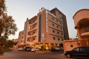 a hotel with cars parked in a parking lot at Hayat Al Zahraa Serviced Apartments in Jeddah