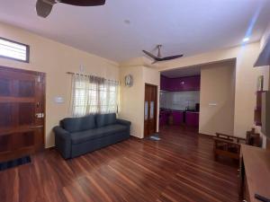 sala de estar con sofá azul y suelo de madera en Soundarya Sapphires en Bangalore
