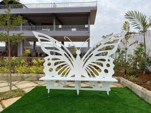 a white bench sitting on the grass in front of a house at Soundarya Sapphires in Bangalore