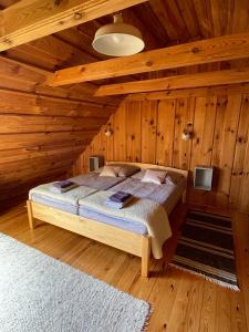 ein Schlafzimmer mit einem Bett in einer Holzhütte in der Unterkunft Őrségi Mi Kis Házunk vendégház in Szalafő