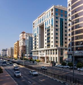 una concurrida calle de la ciudad con coches aparcados frente a edificios altos en Khalidia Palace Hotel Dubai, en Dubái